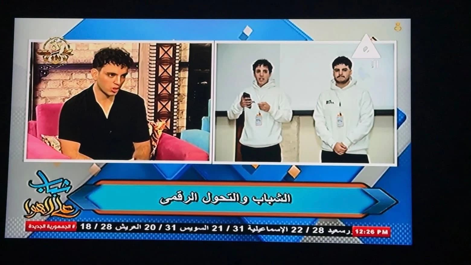 A photograph of the television broadcast showing a Softworks speaker alongside footage of the team